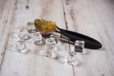 Scoop with fruits by ice cubes on wooden table