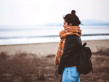 Side view of thoughtful young woman standing at beach