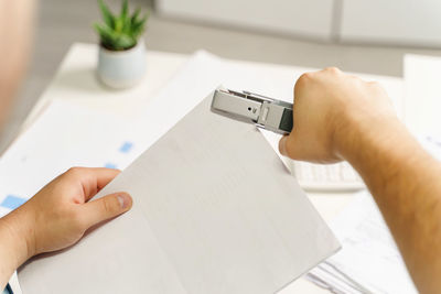 Midsection of person holding paper on table