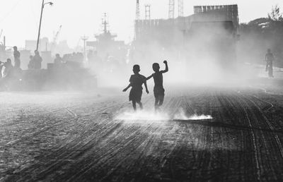 Boys dancing on dirt road during sunny day