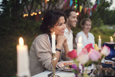 Smiling friends sitting at decorated table in garden party