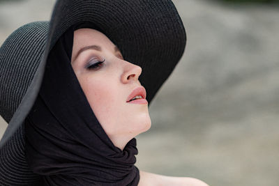 Close-up of thoughtful woman wearing black hat