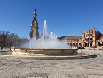Fountain in front of building against clear blue sky