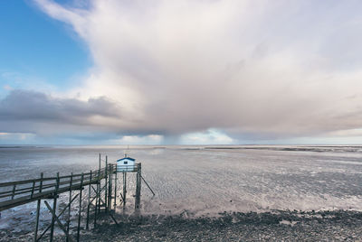 Scenic view of sea and fishing hut against sky