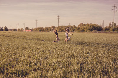 Friends enjoying on grassy field against sky