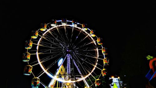 Low angle view of illuminated ferris wheel against sky at night