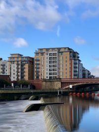 Arch bridge over river against buildings in city against sky