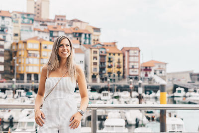 Young woman looking away while standing against cityscape