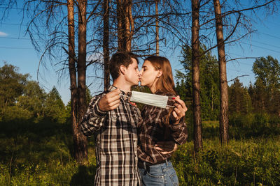 Couple holding mask kissing in forest