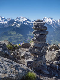 Stack of rocks on snowcapped mountain against sky