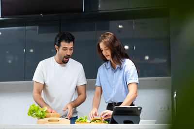 Friends standing by food in kitchen