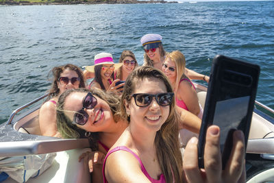 Female friends on top of a boat against the sea in the background. 