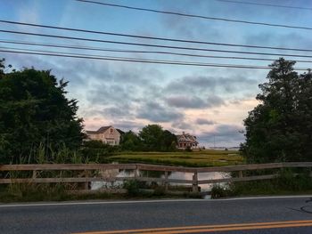 Road by trees and buildings against sky