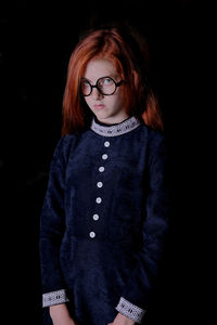 Portrait of girl standing against black background