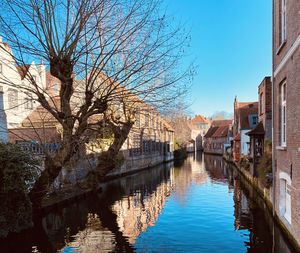 Canal amidst buildings against clear blue sky