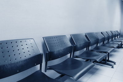 Empty chairs and table against wall