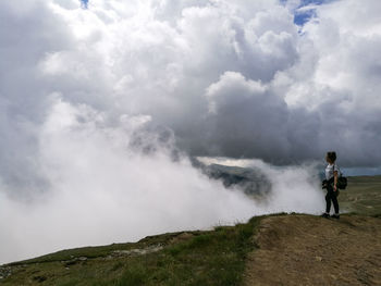 Woman standing on mountain against sky