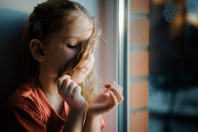 Portrait of girl looking through window