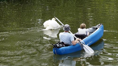 Rear view of man with son kayaking in lake