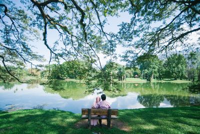 Rear view of couple sitting on seat in lake