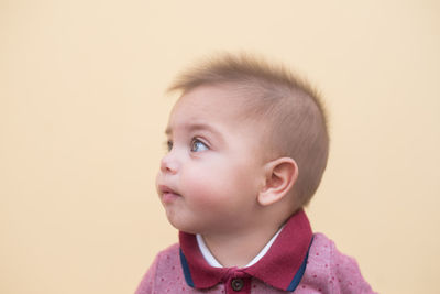 Portrait of cute boy looking away against white background