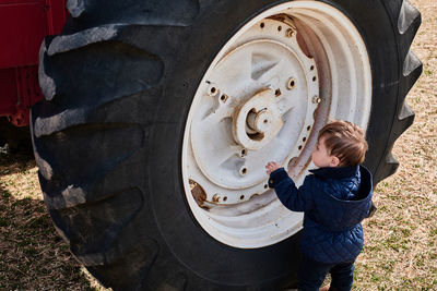 Little boy next to a huge tractor wheel at the county fair