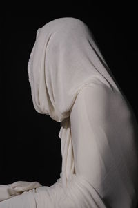 Person wrapped in white fabric against black background