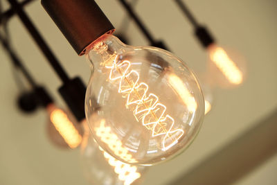 Low angle view of illuminated light bulb on ceiling