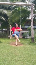 Full length of girl sitting on grass against trees