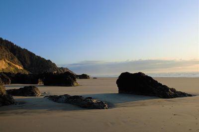 Rocks on beach against sky during sunset