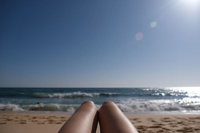 Low section of woman on beach against clear sky