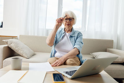 Young woman using laptop while sitting on sofa at home