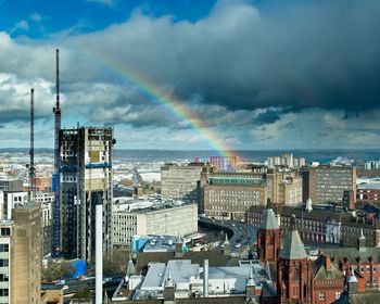High angle view of rainbow over buildings in city against sky