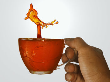Close-up of hand holding drink against white background