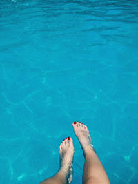 Low section of woman legs in blue swimming pool