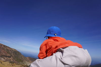 Rear view of man on mountain against sky