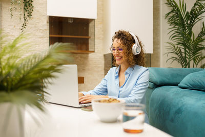 Young woman using mobile phone while sitting at home