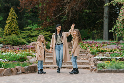 Caucasian schoolgirl daughters walk with their mother in spring in a blooming park