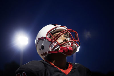 Teenage american football player looking up at illuminated field