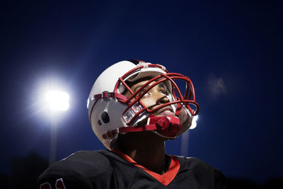 Low angle view portrait of boy against illuminated blue sky