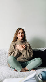 Portrait of young woman sitting on sofa at home