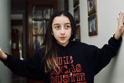 Portrait of teenage girl standing against wall