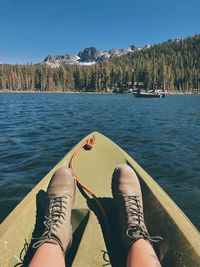 Low section of man relaxing by lake against mountains