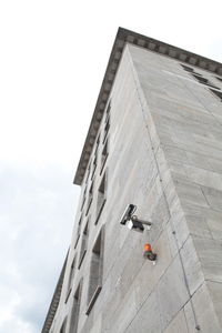 Low angle view of security camera on building against sky