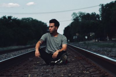 Full length of young man sitting on railroad track