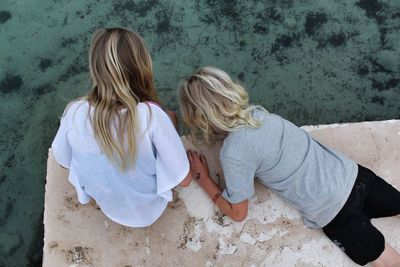 High angle view of siblings on retaining wall over lake