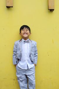 Portrait of smiling girl standing against yellow wall