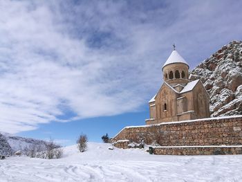Church by building against sky during winter