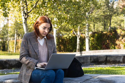 Young businesswoman using laptop at park