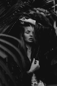 Portrait of young woman standing against plants